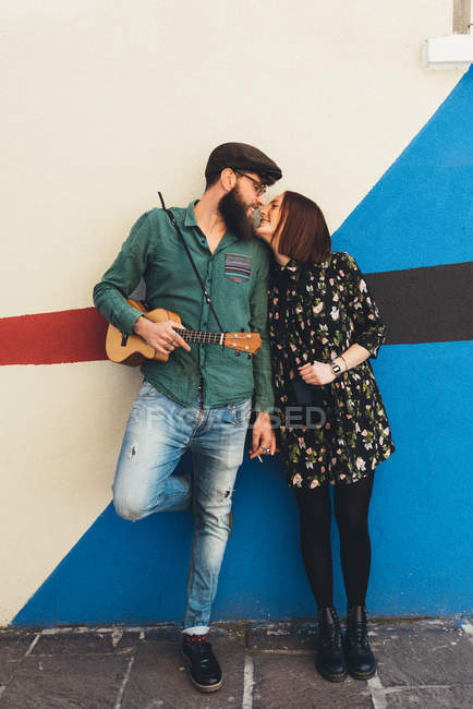 Cool couple leaning against abstract wall gazing at each other — Stock Photo