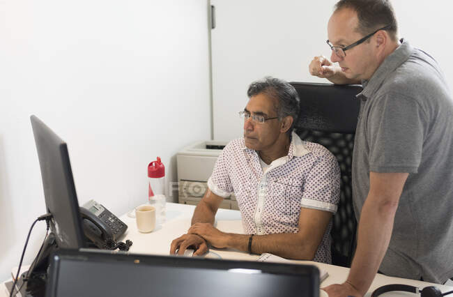 Колеги в офісі дивляться на комп'ютер — стокове фото