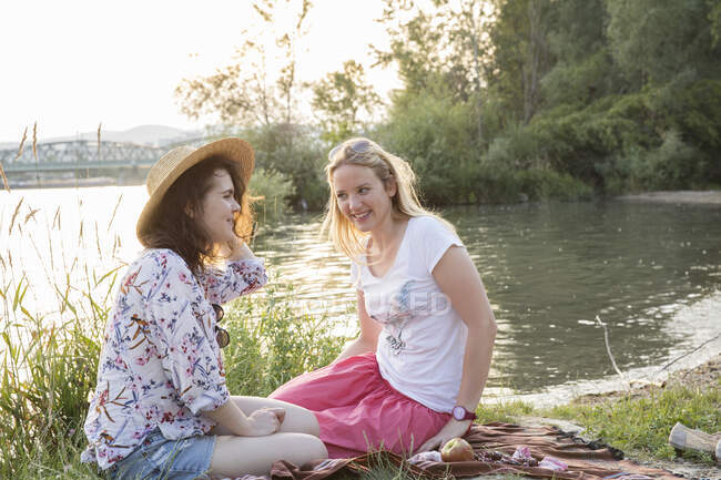 Due amiche rilassanti accanto al lago — Foto stock