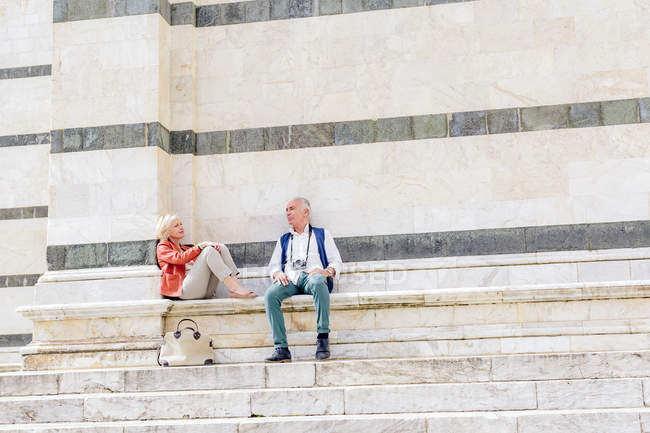 Coppia turistica seduta sulla scalinata del Duomo di Siena, Toscana, Italia — Foto stock