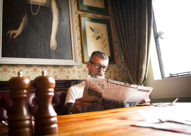 Quirky man reading newspapers in bar and restaurant, Bournemouth, England — Stock Photo