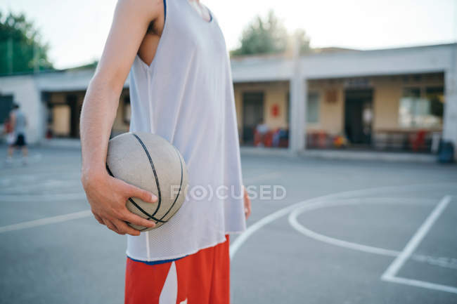 Обрізаний вид людини на баскетбольний майданчик, що тримає баскетбол — стокове фото