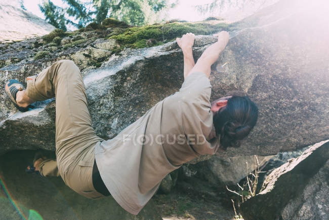 Young male boulderer climbing on edge of boulder — Stock Photo