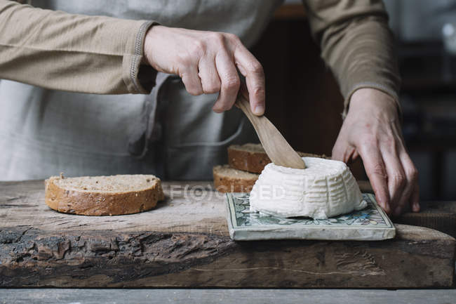 Mulher cortando ricota inteira, fatia de pão na tábua de cortar, seção meio — Fotografia de Stock
