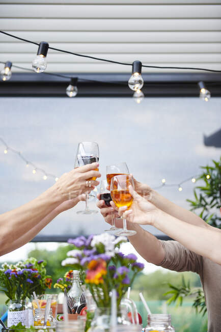 Mãos de homens e mulheres levantando uma torrada de vinho familiar na mesa do pátio — Fotografia de Stock