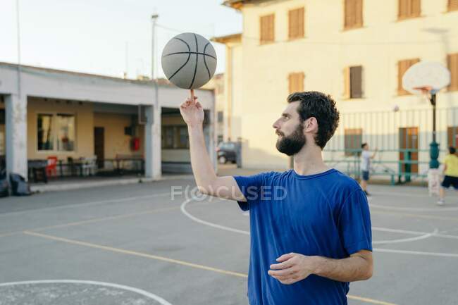 Чоловік обертається баскетболом на пальці — стокове фото