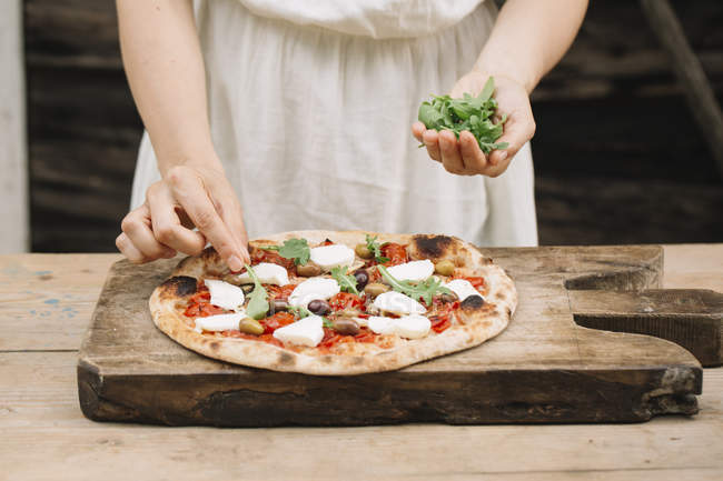 Cropped image of Woman putting herbs on home-made pizza — Stock Photo
