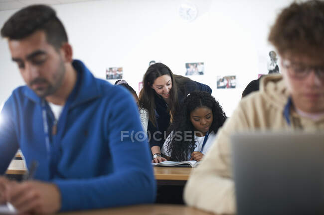 Teacher in classroom helping students study — Stock Photo