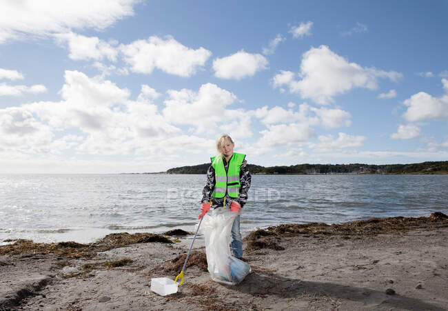Menina em colete de segurança praia de limpeza — Fotografia de Stock