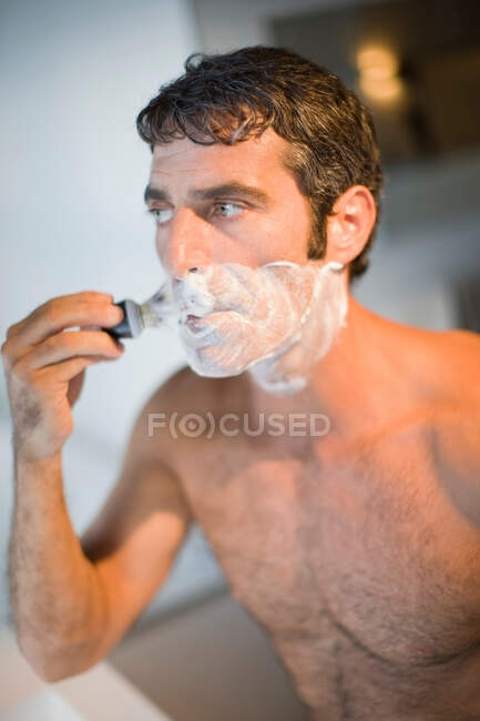 Mann schäumt sein Gesicht im Badezimmer — Stockfoto