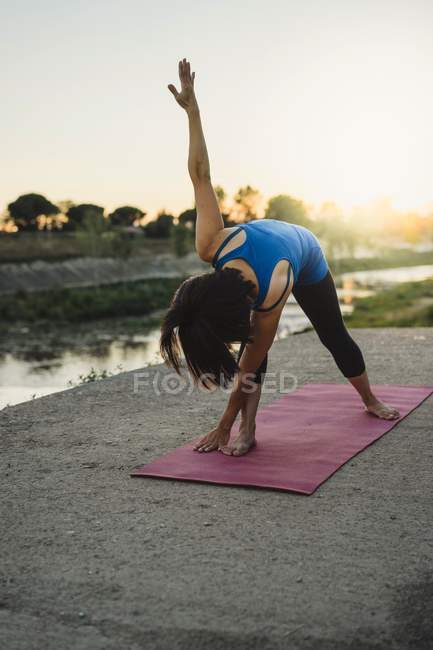 Mature woman outdoors, bending over in yoga position — Stock Photo