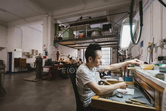 Male jeweller working at jewellery workshop workbench — Stock Photo