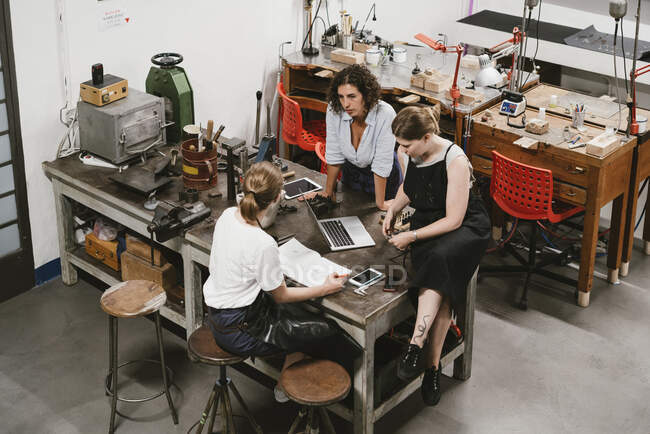 Blick aus der Vogelperspektive: Drei Juwelierinnen diskutieren bei Werkbank-Treffen — Stockfoto