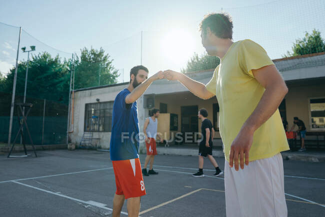 Friends on basketball court doing fist bump — Stock Photo