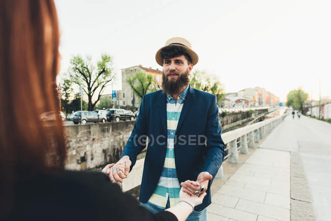 Over shoulder view of man holding girlfriend's hands by city canal — Stock Photo