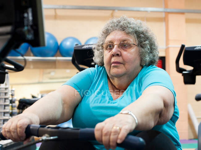 Older woman using rowing machine — Stock Photo