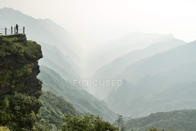 Turista mirando desde el Monte Fanjing formación de rocas, Jiangkou, Guizhou, China - foto de stock
