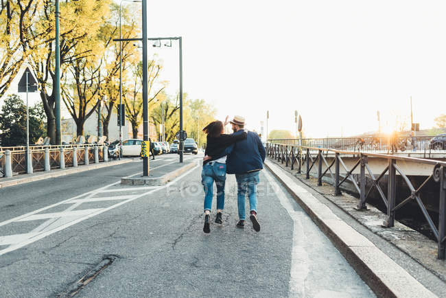 Rear view of couple running by city canal — Stock Photo