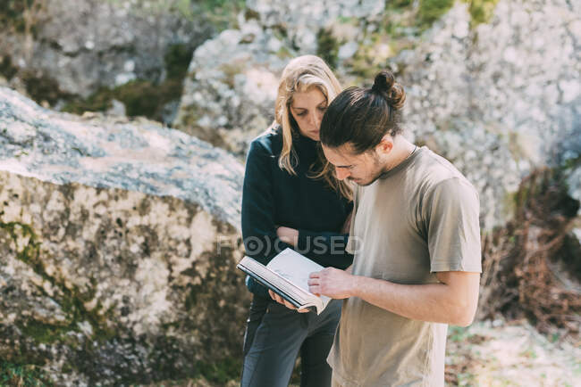 Male and female bouldering friends looking at guidebook, Lombardy, Italy — Stock Photo