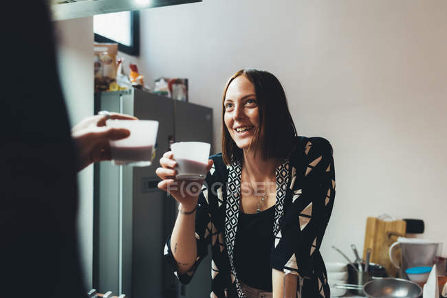 Mujer joven y novio levantando una tostada de café en la cocina - foto de stock