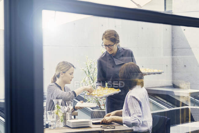 Zwei Geschäftsfrauen werden beim Geschäftsessen vor dem Büro mit Häppchen bedient — Stockfoto