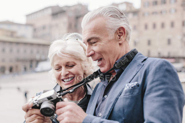Tourist couple reviewing digital camera in town square, Siena, Tuscany, Italy — Stock Photo
