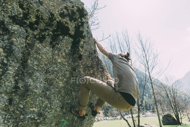 Вид сбоку на молодого человека, карабкающегося по камню — стоковое фото