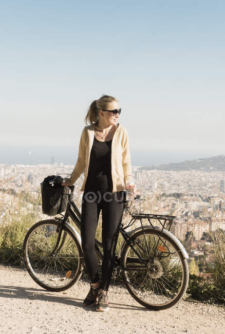 Turismo de mujeres en bicicleta, ciudad de fondo, Barcelona, Cataluña, España - foto de stock