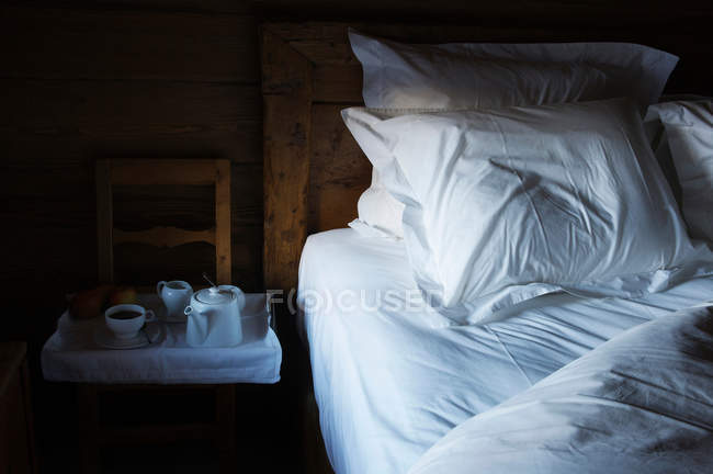 Tray with tea for breakfast standing by bed in morning — Stock Photo