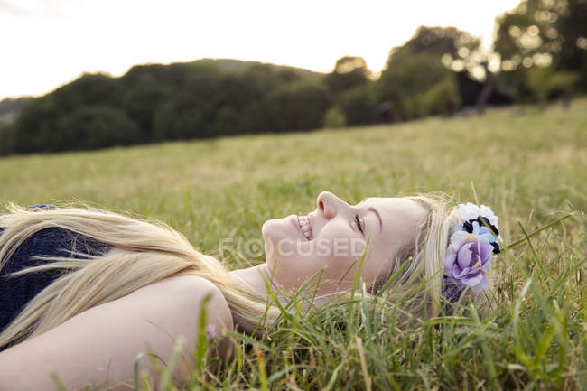 Жінка з квітами в волоссі лежить на траві — стокове фото