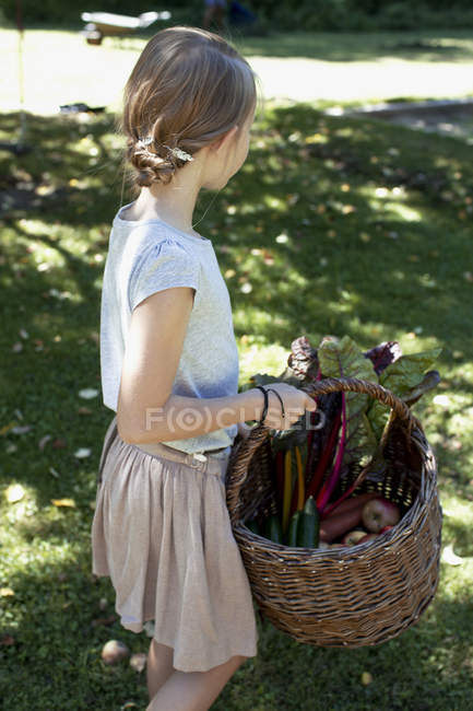 Chica llevando cesta de verduras - foto de stock