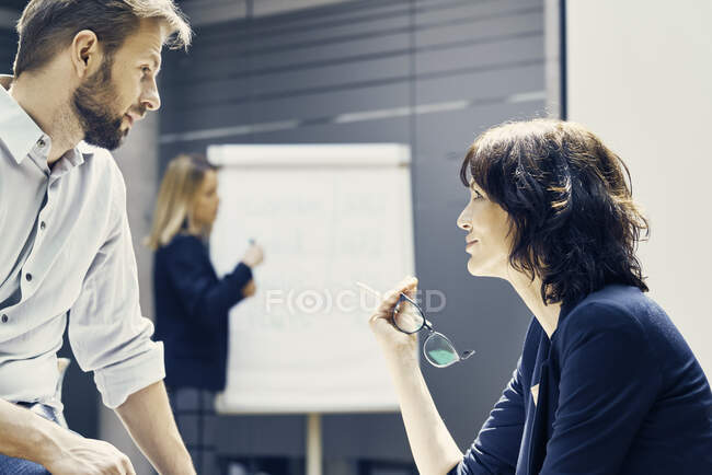 Бізнес-леді і чоловік обговорюють під час презентації офісу — стокове фото