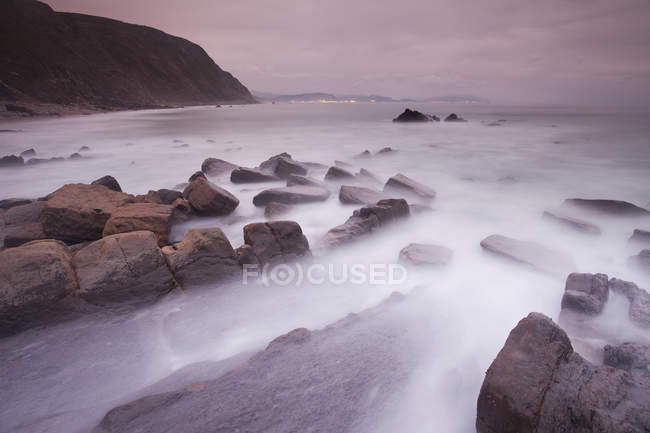 Nebbia rotolamento sulla spiaggia rocciosa — Foto stock