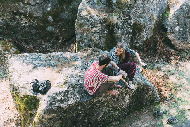 Vista de ángulo alto de dos amigos de boulder sentados en boulder, Lombardía, Italia - foto de stock