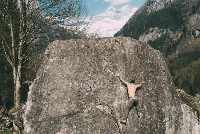 Rückansicht junger Mann klettert auf Felsbrocken — Stockfoto