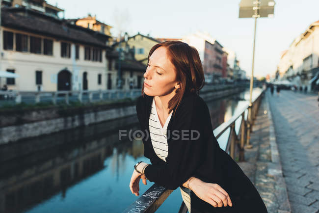 Junge Frau lehnt an Geländer und blickt auf Kanal — Stockfoto