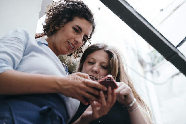 Дві жінки-ювеліри дивляться смартфон у ювелірній майстерні — стокове фото