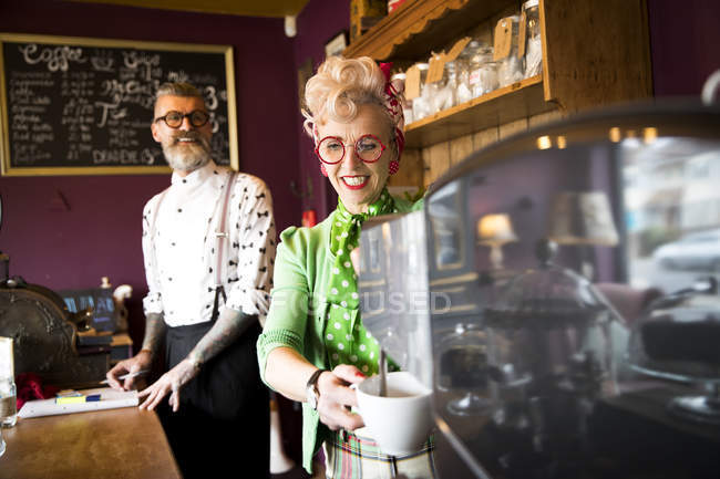 Vintage couple working behind counter in tea room — Stock Photo