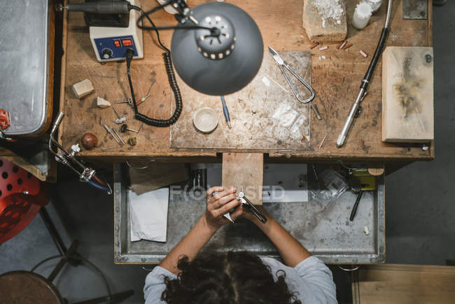 Overhead view of female jeweler using coping saw at workbench — Stock Photo