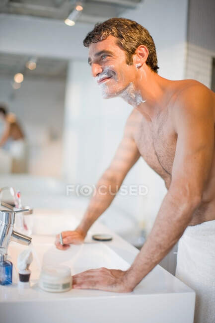 Улыбающийся мужчина бреется в ванной — стоковое фото