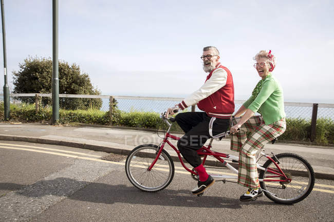 Quirky couple sightseeing on tandem bicycle, Bournemouth, England — Stock Photo