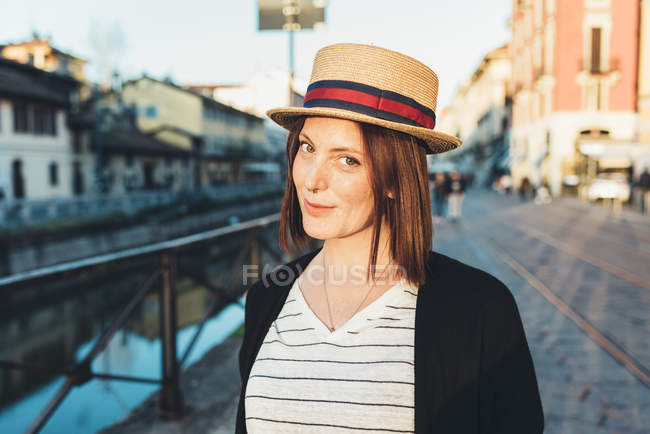Portrait of young woman in straw boater by canal — Stock Photo