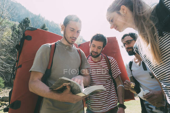 Adultos amigos peñascos mirando la guía, Lombardía, Italia - foto de stock