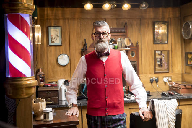 Ritratto di uomo anziano eccentrico nel vecchio negozio di barbiere inglese tradizionale — Foto stock