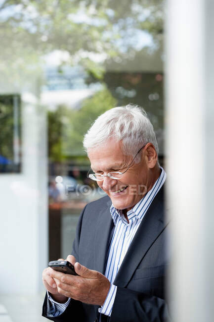 Старший бизнесмен использует мобильный телефон — стоковое фото