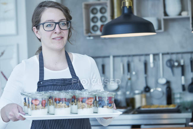 Female chef holding tray of berries desserts — Stock Photo