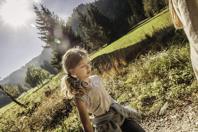 Девушка следует за матерью во время прогулки по освещенному солнцем пейзажу, Бавария, Германия — стоковое фото