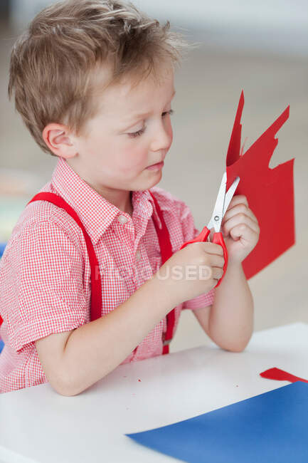 Niño con papel y tijeras - foto de stock