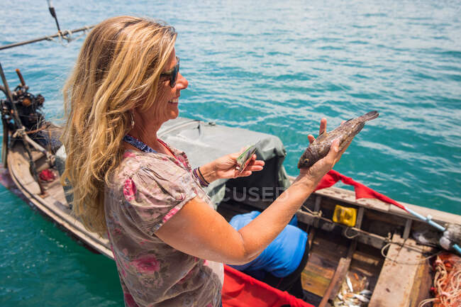 Frau, die mit einem Langschwanzfischerboot Fische hält, Koh Yao Yai, Thailand, Asien — Stockfoto