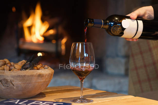 Person pouring wine by fireplace — Stock Photo